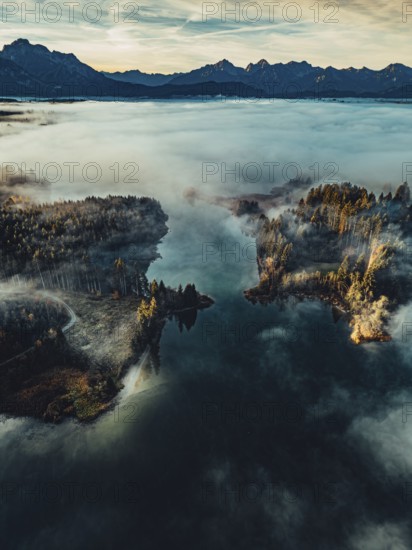 Autumn sunrise in the foothills of the Alps with fog at Illasbergsee and Forggensee near Halblech