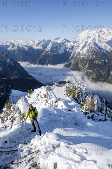 Tourist with camera on a hiking trail, Snow-covered summit of the Jenner with viewing platform in