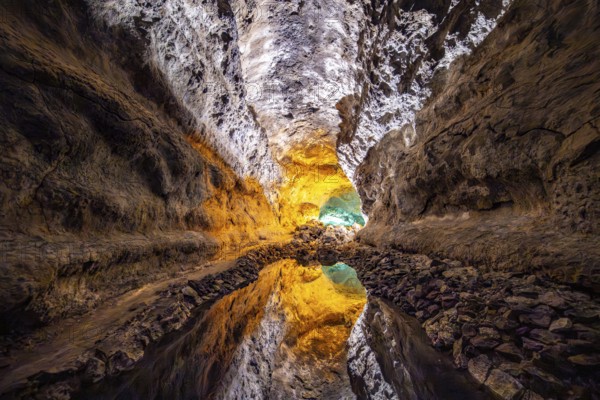 Lava tunnel, illuminated lava cave with perfect reflection in an underground lake, Cueva de los