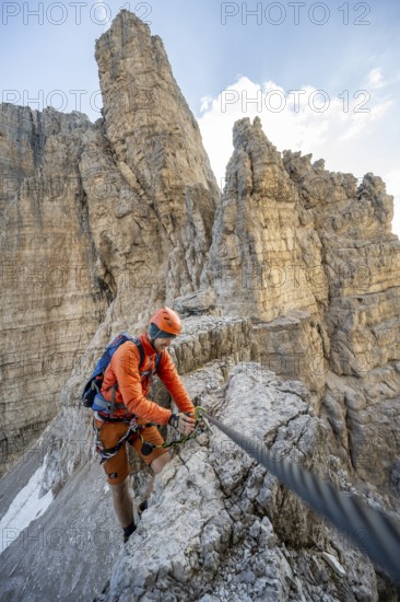 Mountaineer climbs an exposed rock in the secured Via Ferrata Bocciere Centrale via ferrata,
