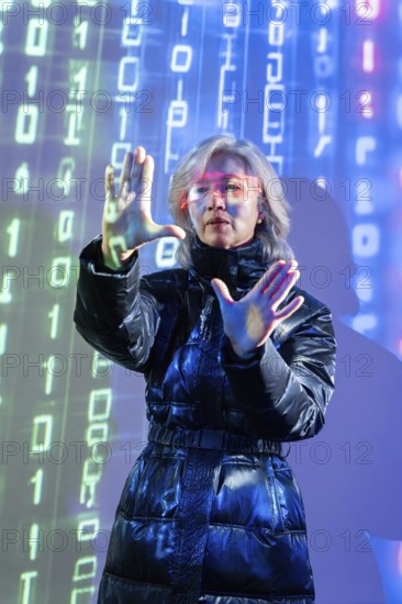 An elderly Asian woman with virtual reality glasses interacts in a digital metaverse environment.