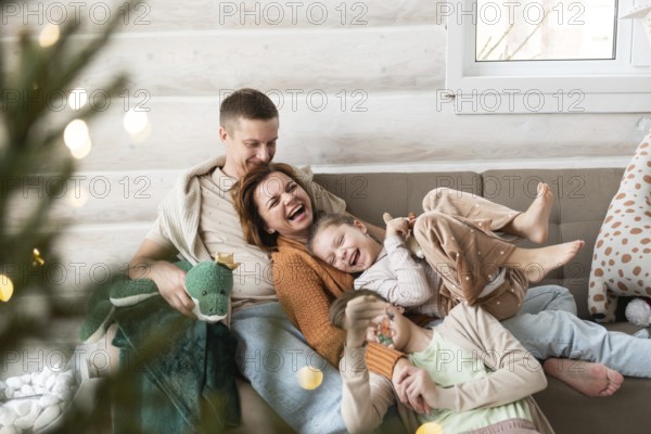 A joyful family celebrates Christmas in a cozy home setting. Two adults and two children, all