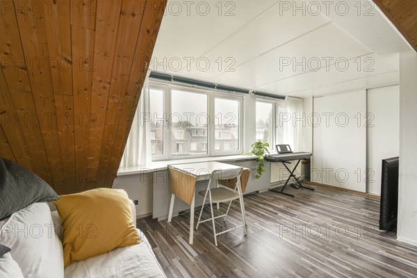 Spacious attic room featuring a slanted wooden ceiling, bright windows with a view, a cozy