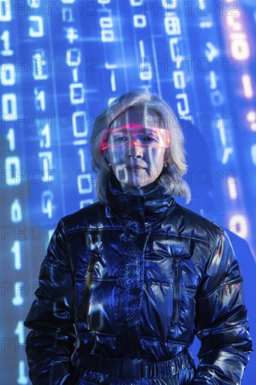 An elderly Asian woman wearing futuristic eyewear is immersed in the metaverse. Blue digital code
