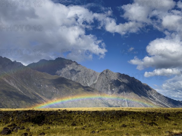A stunning autumn scene at Mount Cook, New Zealand, showcasing a vibrant rainbow arching over lush