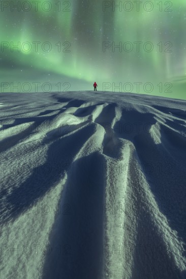 Unrecognizable person stands alone under the mesmerizing Aurora Borealis on a snowy landscape