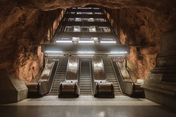 View of escalators at a Stockholm subway station, surrounded by cave-like rock formations. The