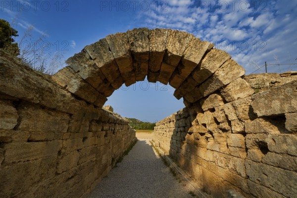 Crypt, vaulted walkway to the stadium, old stone arch leading through massive walls under a blue
