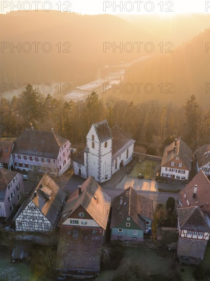 Half-timbered houses and a church in warm sunset light look idyllic and peaceful, Zavelstein, Calw