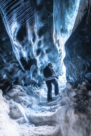 A person is walking through a cave with blue walls. The cave is very cold and the person is wearing