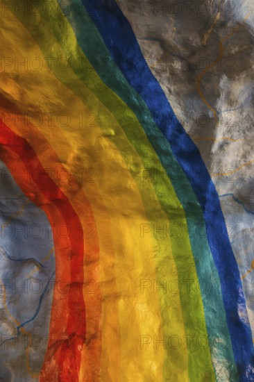 A colorful rainbow mural painted on a textured wall in Stockholm. The vivid hues contrast with the