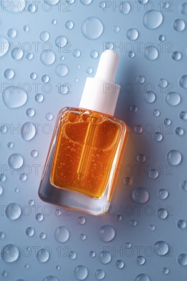 A bottle of vitamin C serum with a pipette, filled with vibrant orange liquid, is set against a