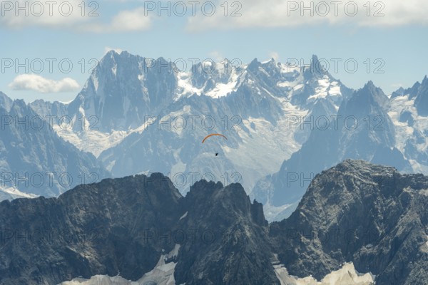 A lone paraglider glides gracefully above the rugged peaks of the French Alps near Chamonix and