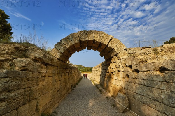 Crypt, vaulted entrance to the stadium, ancient stone arch on a narrow hiking trail under a clear