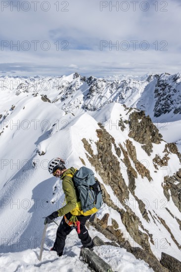 Mountaineer on the summit of Piz Grialetsch in winter, view of mountain panorama with snow, Grisons