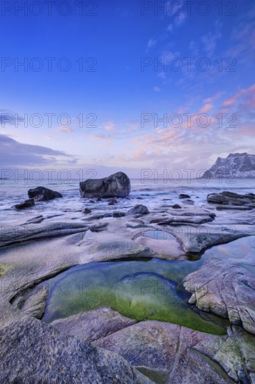 Rocks on beach of fjord of Norwegian sea in winteron sunset. Utakliev beach, Lofoten islands,