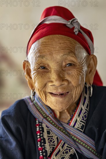 Portrait of an elderly woman with a traditional headscarf and smiling face, large Buddha statue at