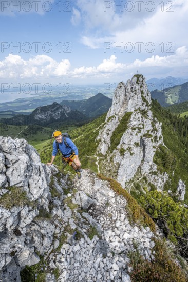 Climber on a climbing tour, on a mountain ridge, behind the summit of the Kampenwand with summit