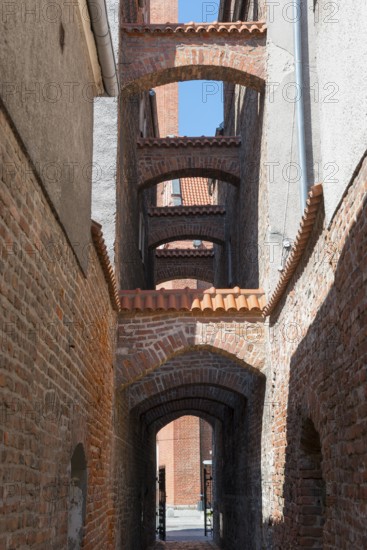 A narrow, arched passageway made of bricks with historical flair, 13th century church path, Elblag,