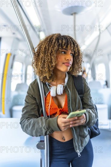 Vertical portrait of a beauty confident latin woman with curly hair and casual clothes using phone