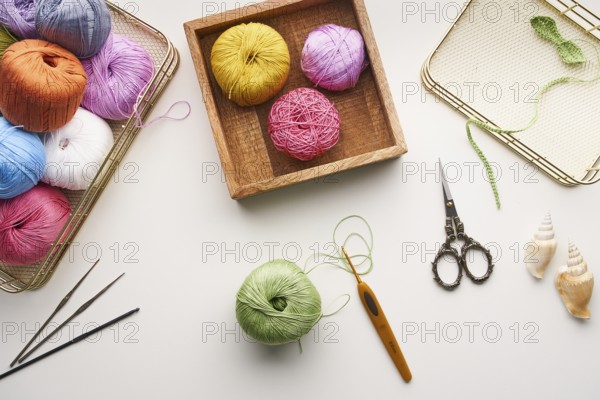 Top view of various colored yarns, crochet hooks, and ornate scissors arranged for needlework and