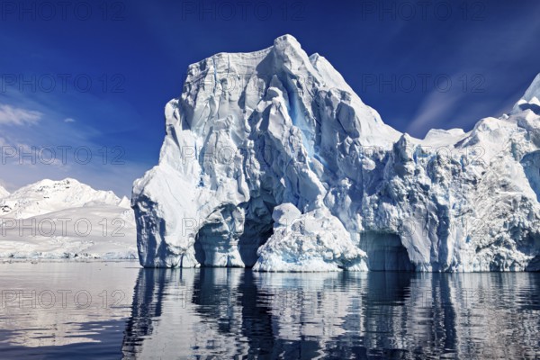 Imposing icebergs are reflected in the calm water under a clear blue sky, icebergs in the Southern