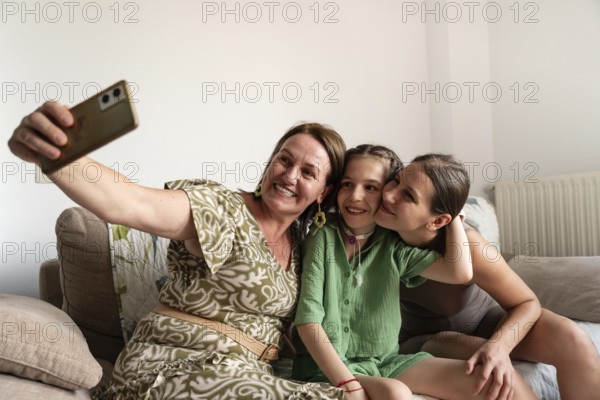 A joyful family is gathered on the couch, taking a selfie with a young girl who has a tracheostomy.