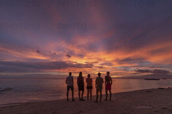 Back view silhouette of unrecognizable friends standing on a beach in the Philippines, watching a