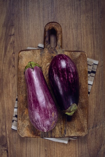 Purple and white eggplant, on a wooden chopping board, top view, raw eggplant, no people