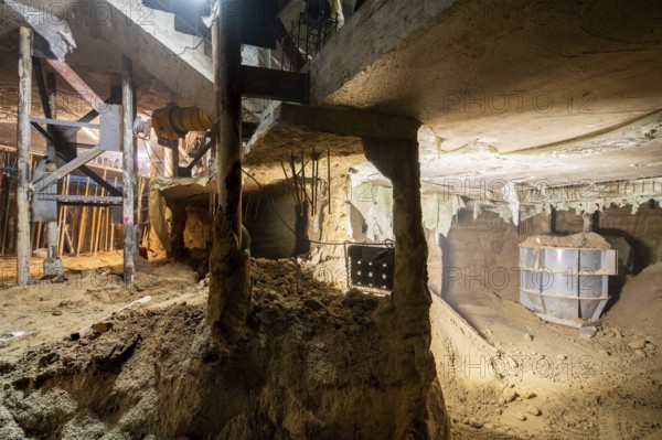 Illuminated underground construction site displaying active excavation work. The scene features