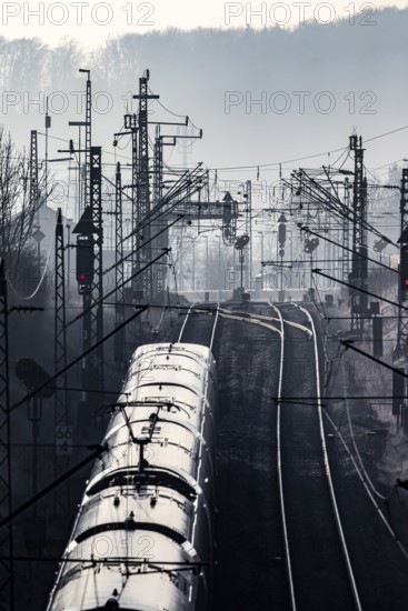 Deutsche Bahn AG tracks with ICE train against the light. Overhead line, signals and infrastructure