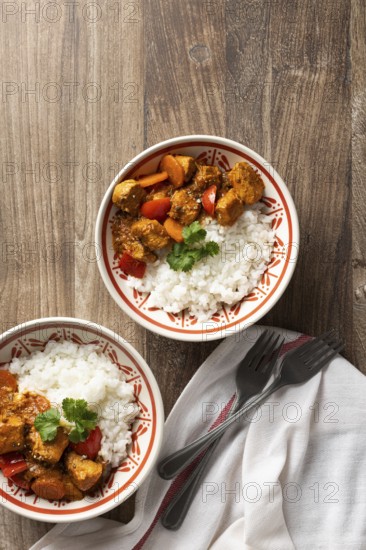 Top view of two bowls of flavorful Hungarian pork goulash with rice, served on a wooden table. The