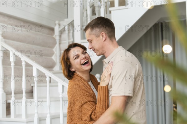 A joyful woman and a smiling man are engaging closely in a warm embrace in an elegantly decorated