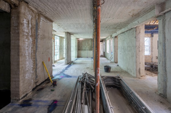 Unfinished building interior showcases raw concrete walls, scattered tools, and construction