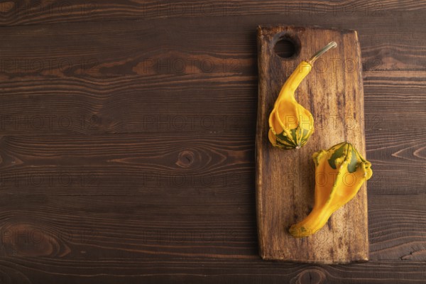 Two decorative orange Pumpkins on cutting board on brown wooden background, top view, flat lay,
