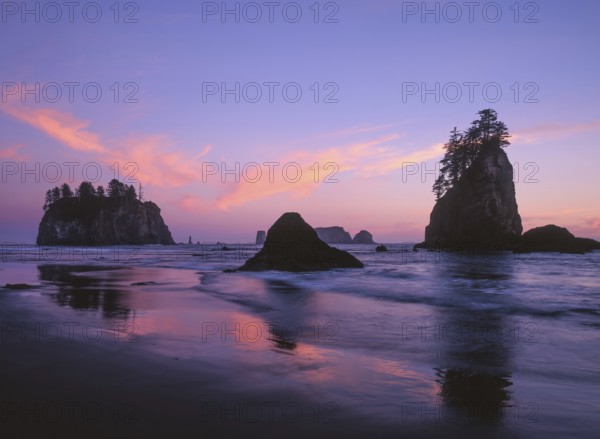 The sky glows in shades of pink and purple as the sun sets over Second Beach, with sea stacks