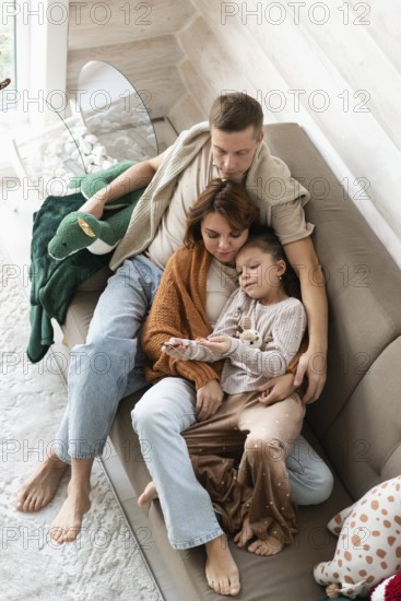 Top view image of a family of four celebrates Christmas in a warm, cozy setting. The mother,