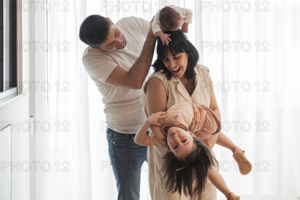 Happy young family shares joyful moments at home. The father holds a newborn while the mother