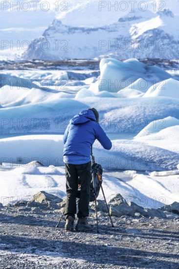 A photographer photographing the floating icebergs in the Jokulsarlon glacier lagoon in Iceland.