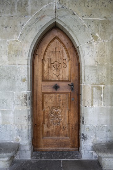 Wooden door with carvings and religious symbols in stone arch, Gothic architecture in the cloister