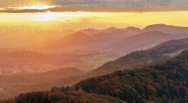 View of an autumnal forest from the Gisliflue, behind the Jurassic foothills in the light of the