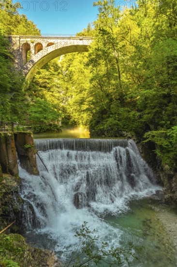 Stunning waterfall cascading beneath a stone bridge in the picturesque vintgar gorge near bled,