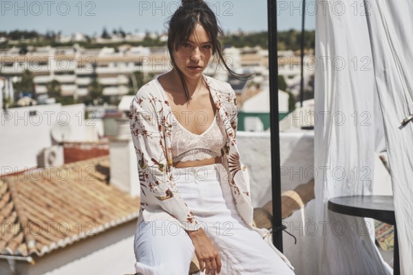 A stylish woman enjoys a sunny day on a rooftop, wearing trendy summer fashion The urban backdrop