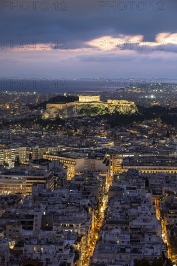 View over the sea of houses of Athens, illuminated Parthenon temple on the Acropolis, dramatic