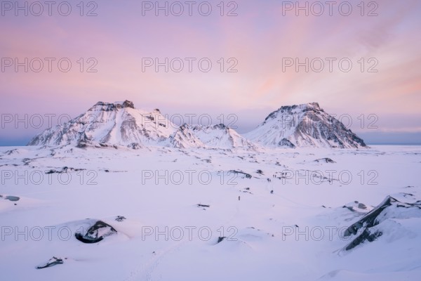 A breathtaking view of Katla Glacier's rugged snow-covered mountains beneath a pastel pink sunrise