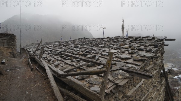 Stone roof of an old building in a foggy mountain village, trekking at Annapurna Circuit, Manang,