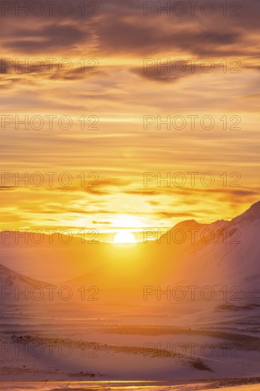 A breathtaking view of a vibrant winter sunset illuminating snow-covered mountains in Iceland. The
