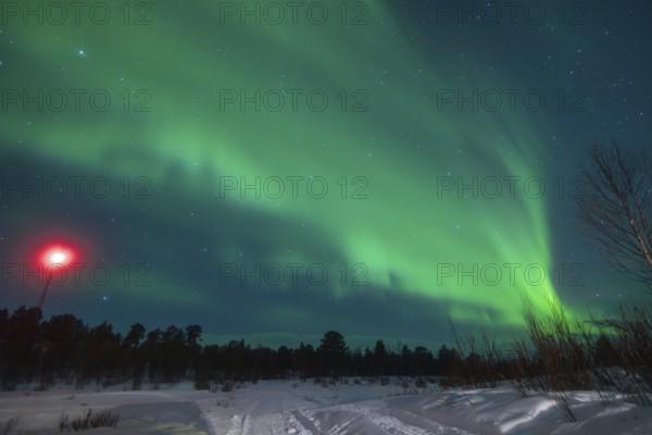 Captivating view of the Aurora Borealis shimmering above a snow-clad landscape near Kiruna, Sweden,