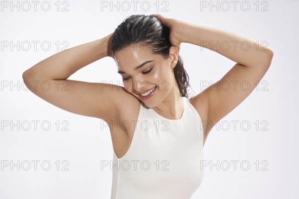 A female model in a white bodysuit enjoys a refreshing moment in a studio, her gaze looking down as