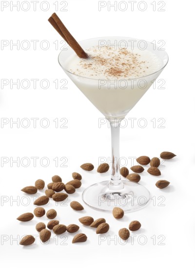 Cocktail in a martini glass in front of a white background, a cinnamon stick and cinnamon powder as